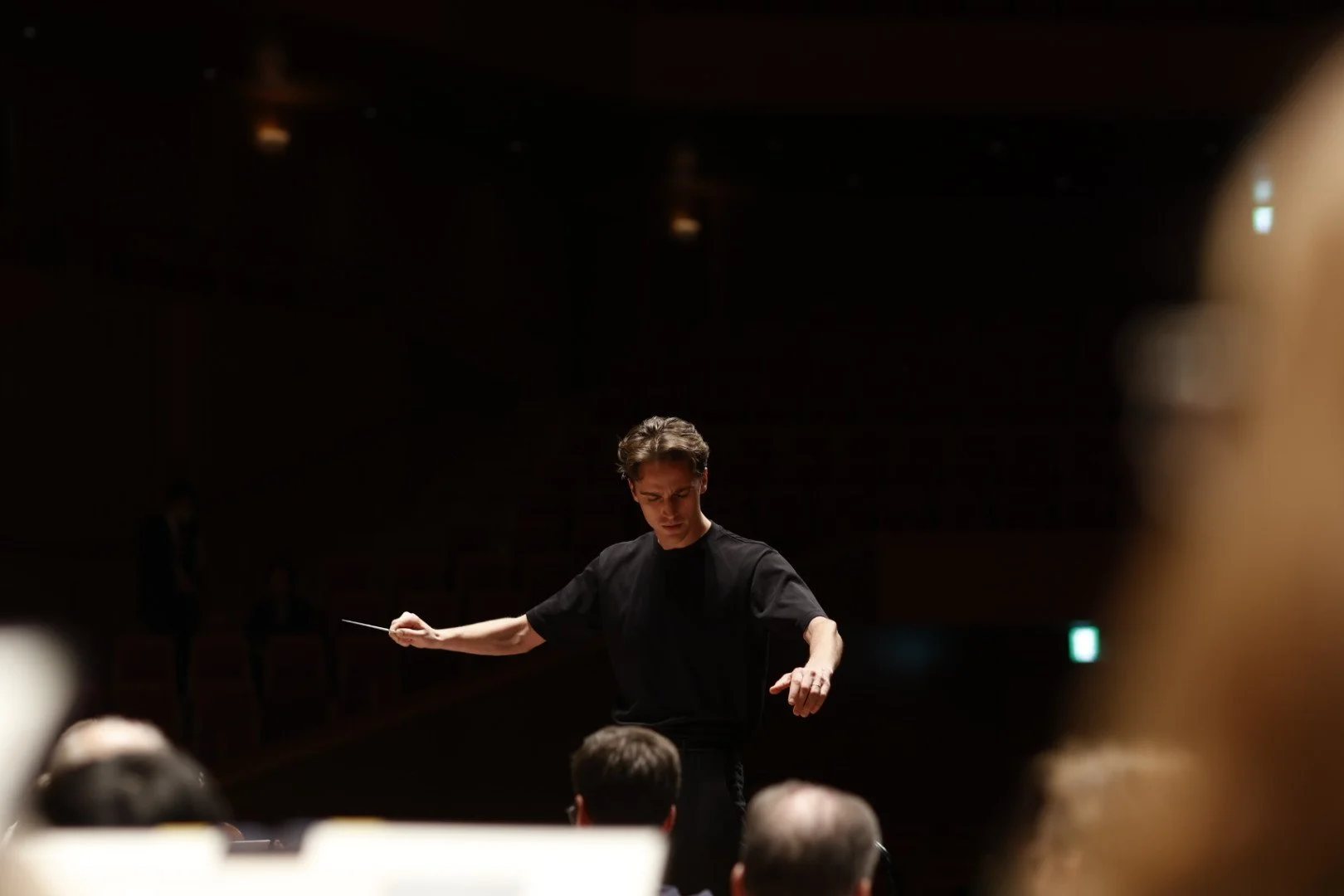 Sasha Scolnik-Brower conducting in a darkened concert hall